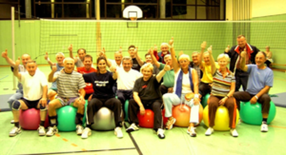 Gruppenfoto von ca. 20 Personen auf Gymnastikbällen in einer Turnhalle